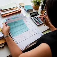 Business owner reviewing financial documents and calculator, showing how Odoo Malaysia provides live visibility into inventory, cash flow, and business numbers.