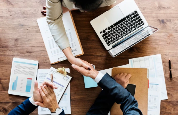 Business handshake over office desk representing Odoo implementation services and Odoo ERP implementation with end-to-end project ownership.